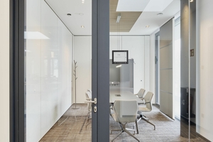  Der luftige Neubau setzt im Innenbereich ganz auf die raumhohen, transparenten Glas-Trennwandsysteme, die das Licht optimal in die moderne Arbeitsumgebung bringen. 