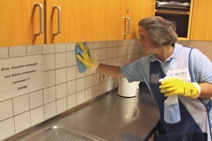  Vorarbeiterin Raluca Gergely demonstriert, wie die Systemlösung mit dem passenden blauen Mikro­faser-Tuch in der Küche funktioniert. Aus Gründen der Arbeitssicherheit werden Handschuhe getragen 