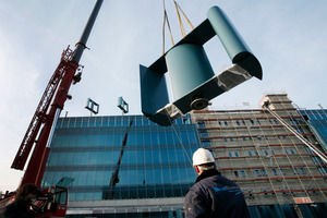  Ein Kran hievt eines der 16 kleinen Windkrafträder auf das Dach der neuen Hauptverwaltung 